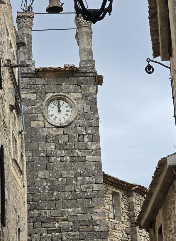 Farol de hierro y torre del reloj en un callejón de piedra