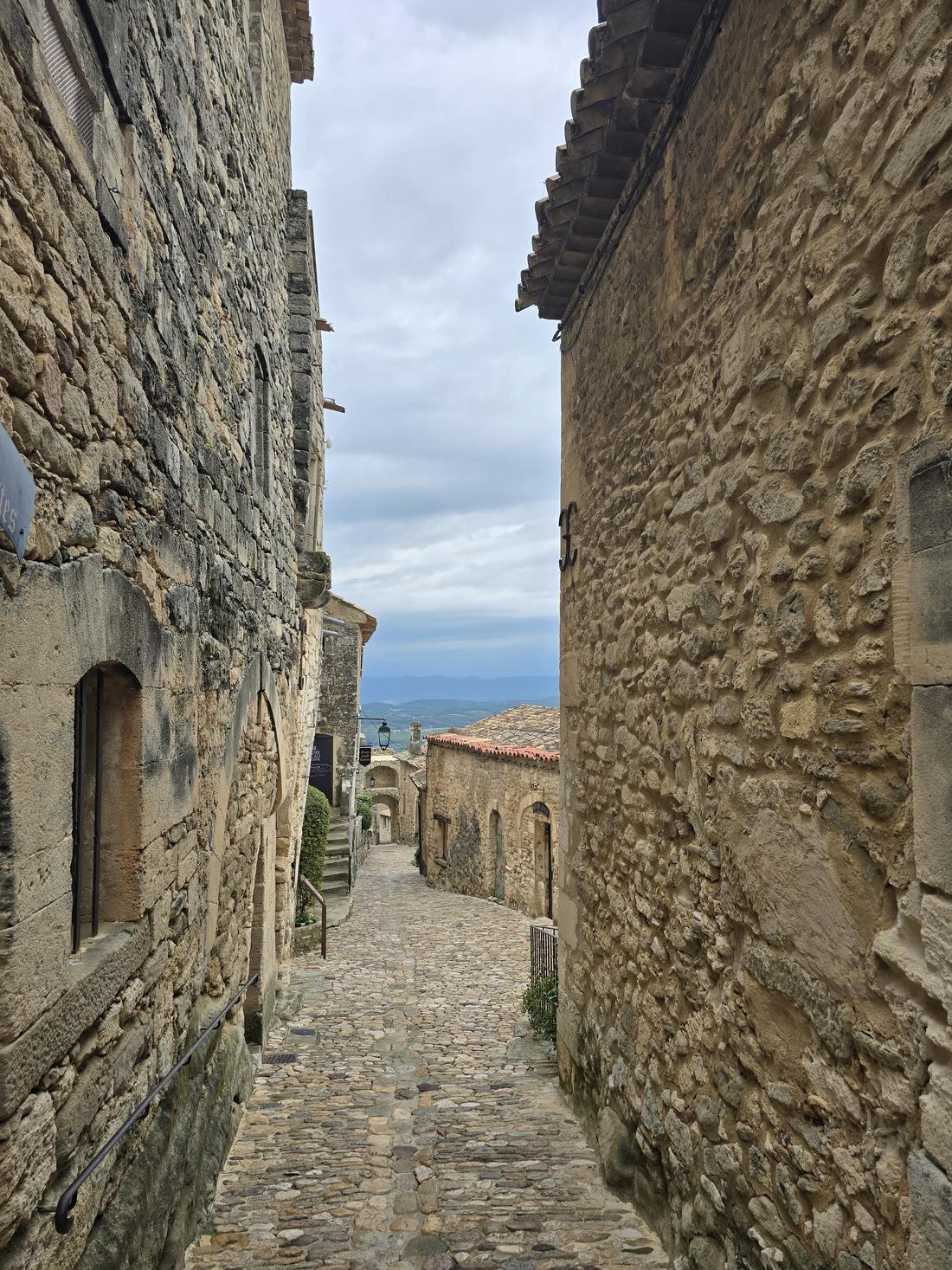 Callejón empedrado de un pueblo de piedra que se abre hacia el valle